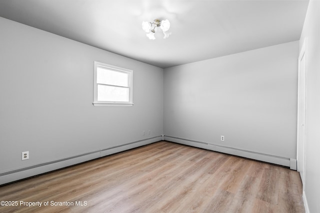 empty room featuring a baseboard radiator and light hardwood / wood-style flooring