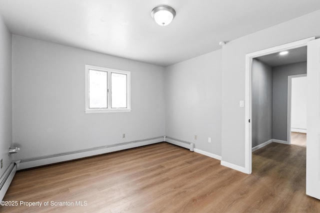 unfurnished room featuring baseboard heating and wood-type flooring