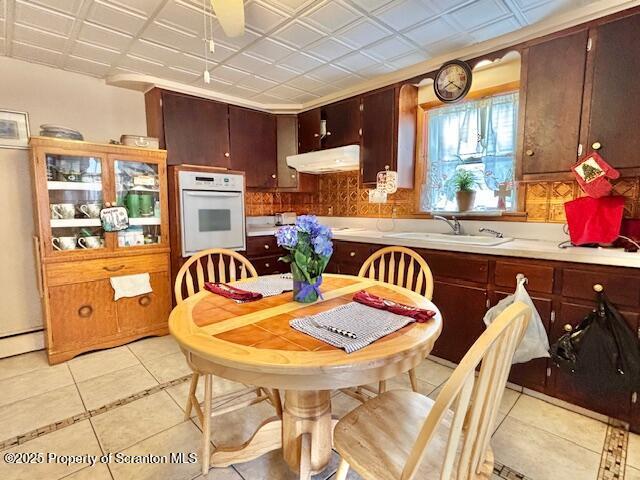 kitchen with an ornate ceiling, white oven, light countertops, a sink, and under cabinet range hood