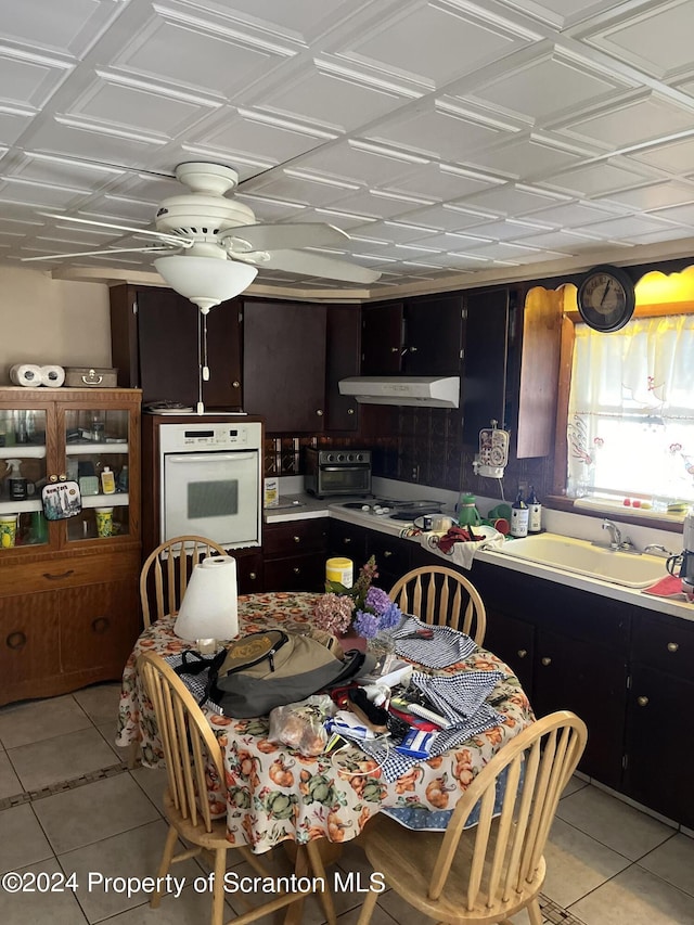 kitchen featuring oven, light tile patterned flooring, and sink