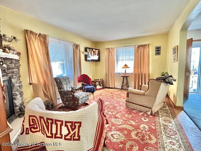 sitting room with carpet floors, arched walkways, and a fireplace