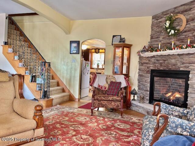 living area featuring stairs, a fireplace, and arched walkways