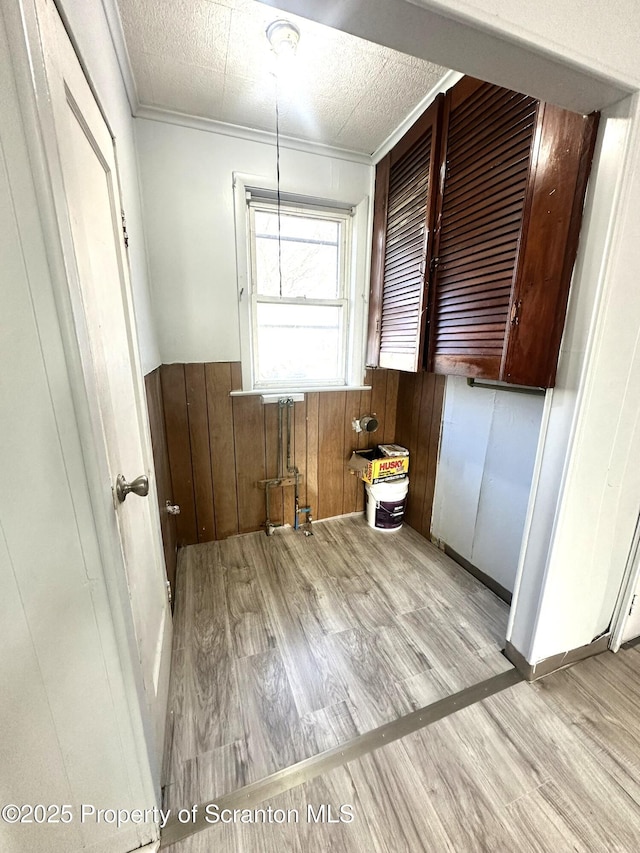 interior space featuring a textured ceiling, wood finished floors, and wainscoting