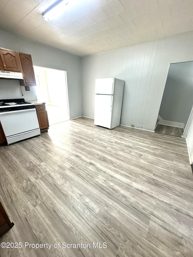 kitchen featuring white appliances, light countertops, light wood finished floors, and under cabinet range hood