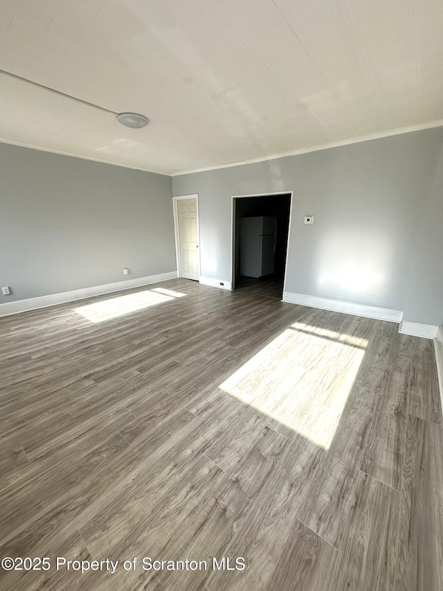 spare room featuring baseboards, wood finished floors, and ornamental molding