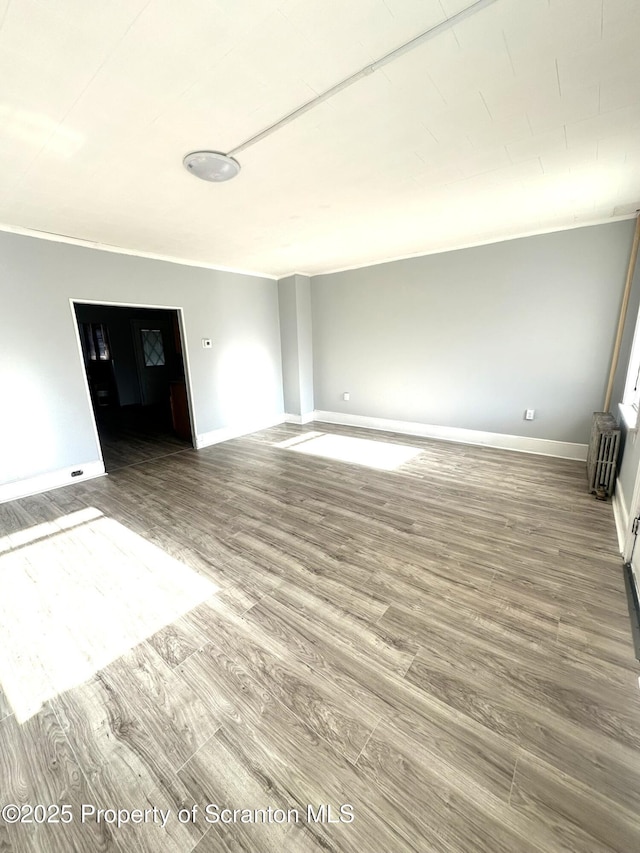 unfurnished room with baseboards, wood finished floors, and radiator heating unit