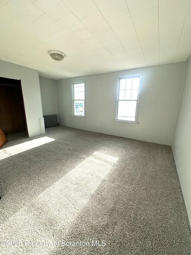 unfurnished bedroom with carpet flooring and radiator