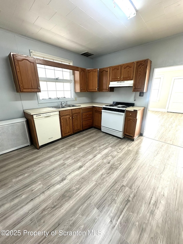 kitchen with visible vents, light wood-style flooring, under cabinet range hood, white appliances, and light countertops