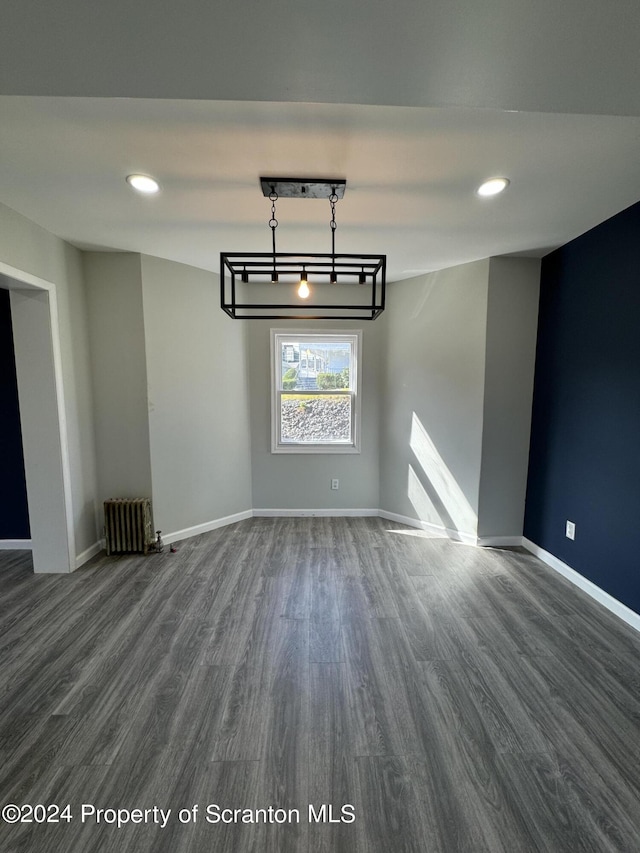 unfurnished dining area featuring dark hardwood / wood-style flooring and radiator