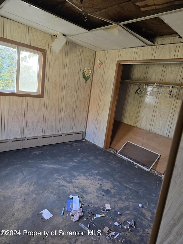 unfurnished bedroom with a baseboard radiator and wooden walls