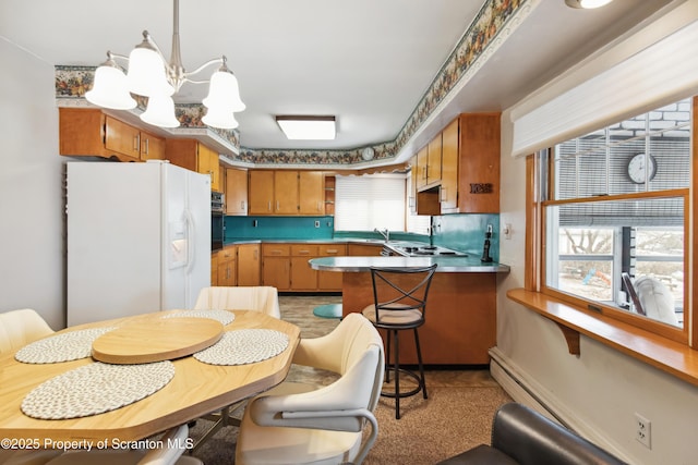 kitchen with kitchen peninsula, white refrigerator with ice dispenser, oven, an inviting chandelier, and stainless steel gas cooktop