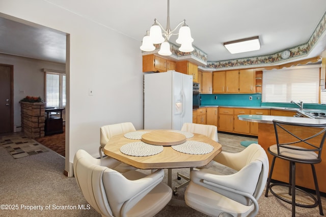 kitchen featuring oven, a chandelier, white refrigerator with ice dispenser, light carpet, and sink