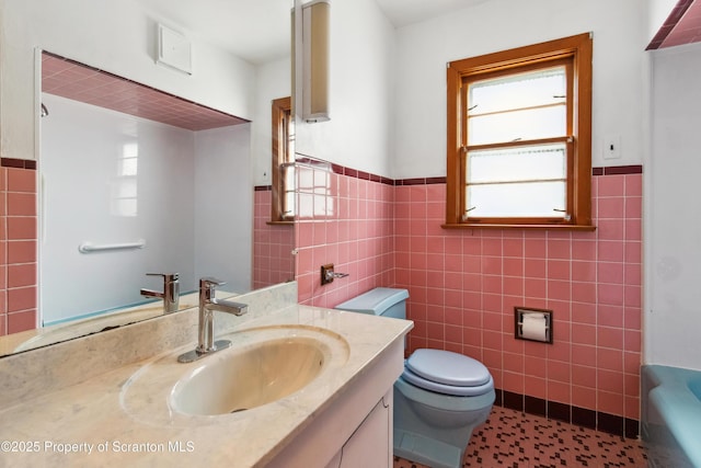 bathroom featuring a washtub, tile walls, toilet, and vanity