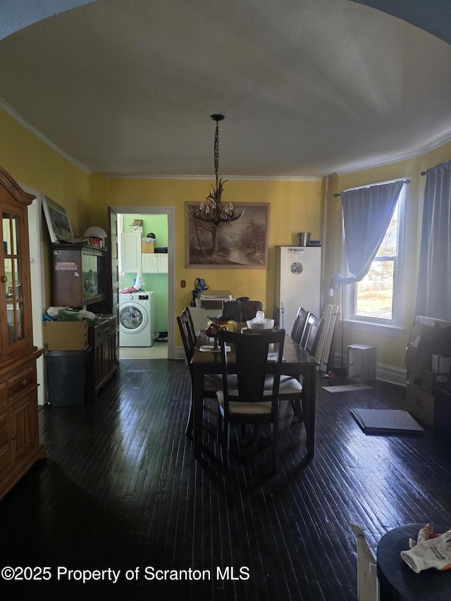 dining room with dark hardwood / wood-style flooring, washer / clothes dryer, and ornamental molding