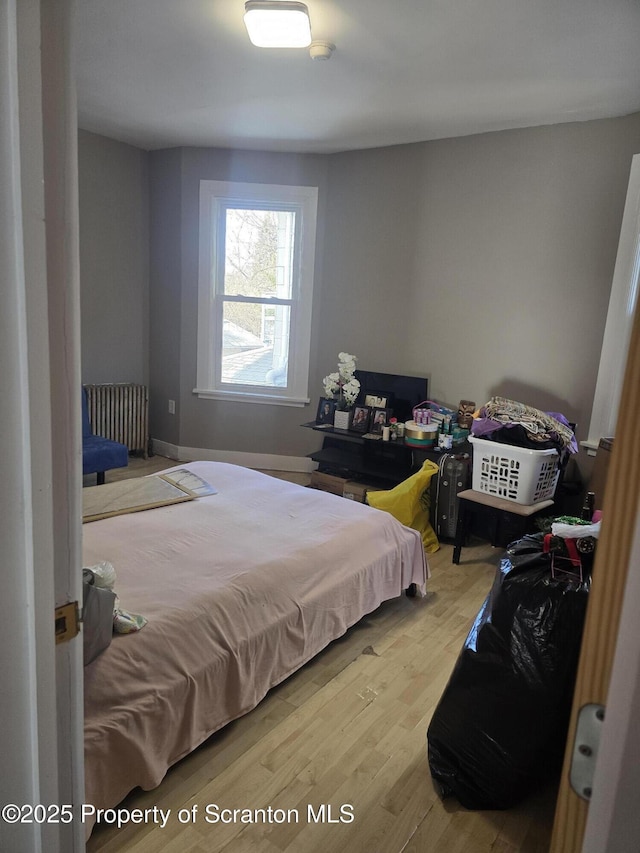 bedroom featuring radiator and hardwood / wood-style flooring