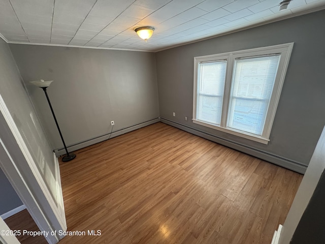 spare room featuring ornamental molding, a baseboard radiator, and light hardwood / wood-style flooring