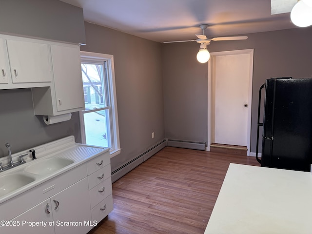 kitchen featuring black refrigerator, white cabinetry, baseboard heating, and light wood-type flooring