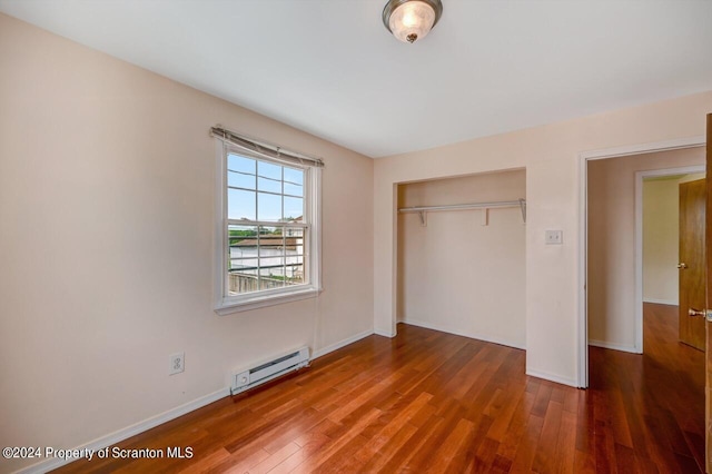 unfurnished bedroom featuring a baseboard radiator, a closet, and hardwood / wood-style flooring