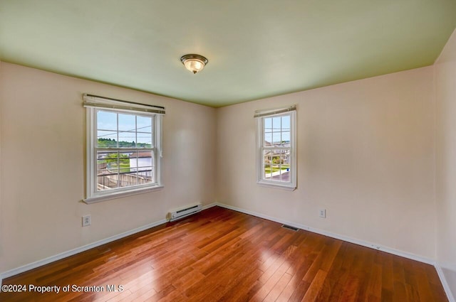 unfurnished room featuring a wealth of natural light, a baseboard radiator, and hardwood / wood-style flooring