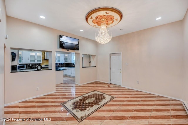 interior space with light tile patterned flooring, a baseboard heating unit, and an inviting chandelier