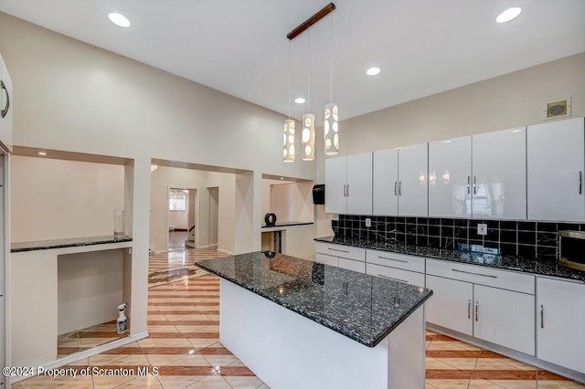 kitchen with white cabinets, dark stone countertops, hanging light fixtures, and tasteful backsplash