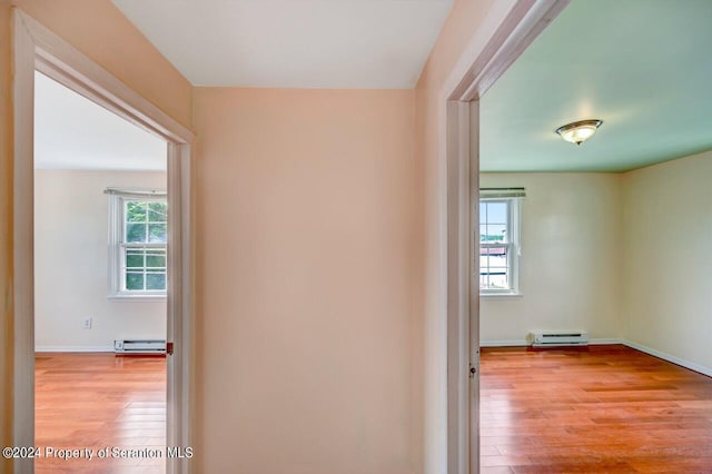 corridor featuring light wood-type flooring, plenty of natural light, and baseboard heating