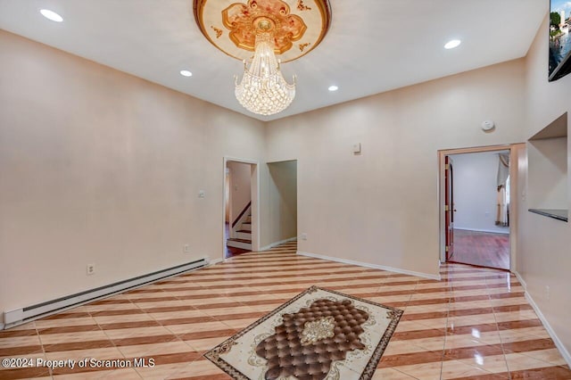 spare room with a chandelier, a towering ceiling, and a baseboard radiator