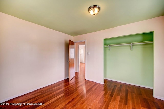 unfurnished bedroom with dark hardwood / wood-style flooring and a closet