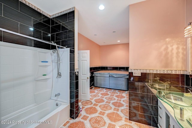 bathroom featuring tiled shower / bath, vanity, tile patterned floors, and tile walls