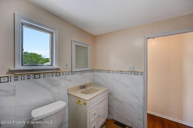 bathroom featuring vanity, toilet, and tile walls