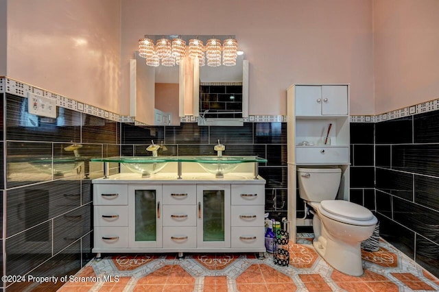 bathroom featuring vanity, tile patterned floors, toilet, tile walls, and a notable chandelier