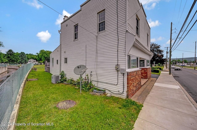 view of side of home featuring a yard and cooling unit