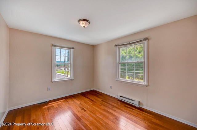 unfurnished room featuring light hardwood / wood-style flooring and a baseboard heating unit