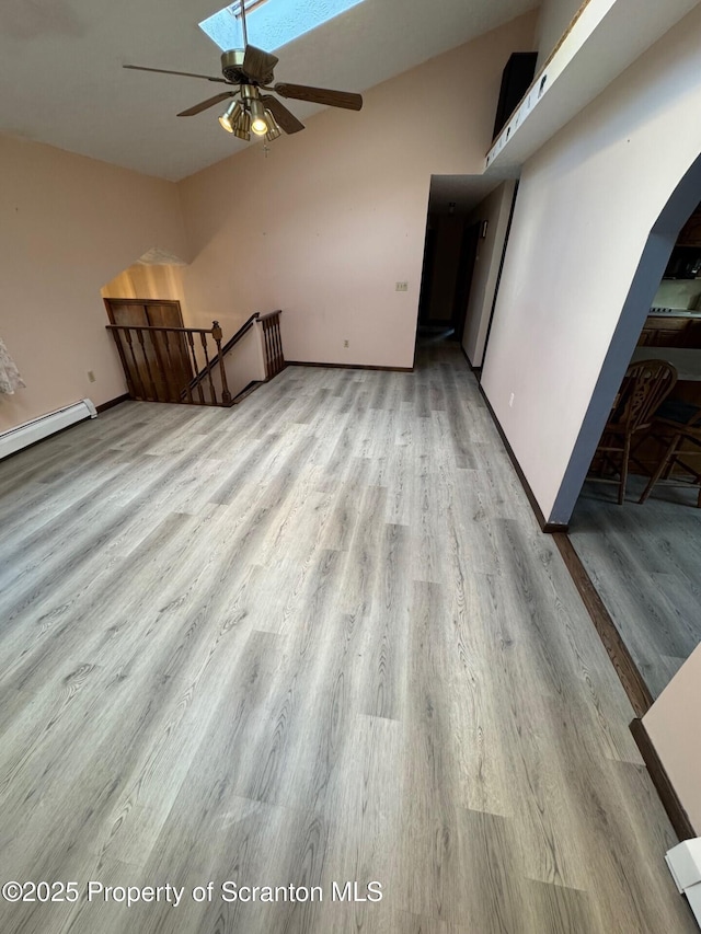 unfurnished living room with ceiling fan, baseboards, vaulted ceiling, and wood finished floors