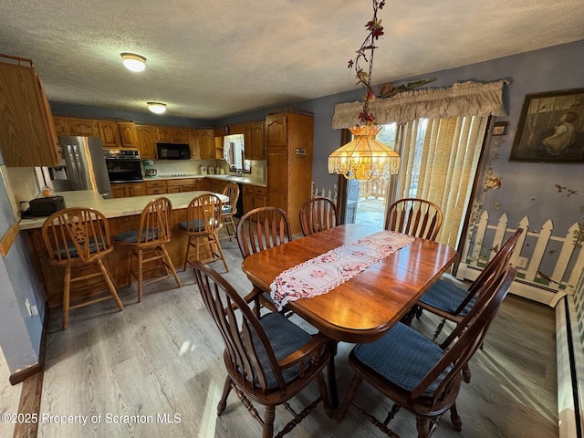 dining space with a textured ceiling and light wood finished floors