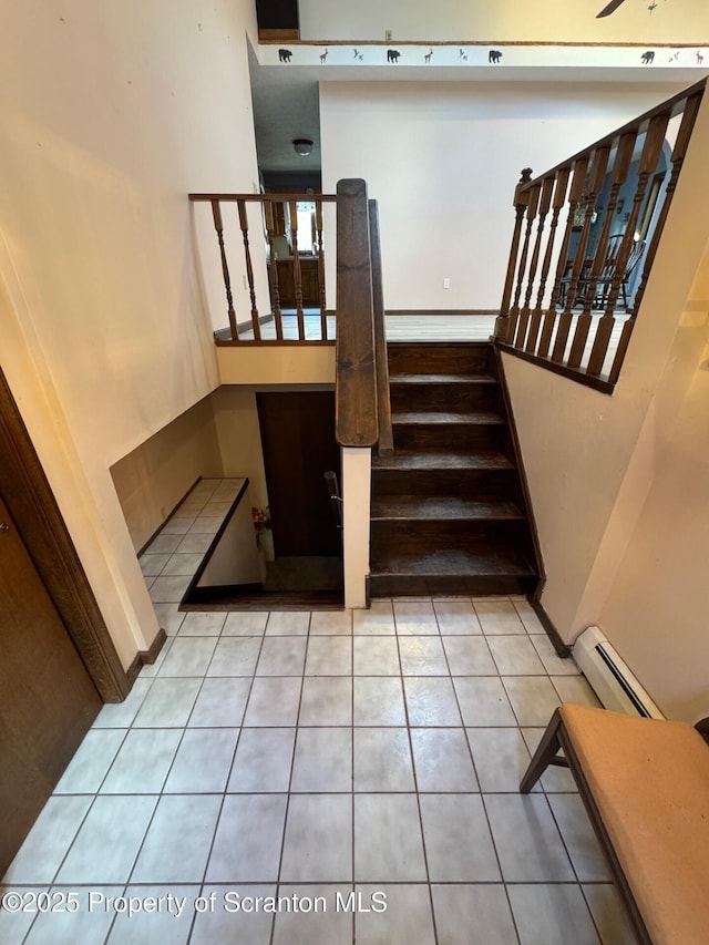 stairway with a baseboard heating unit and tile patterned floors