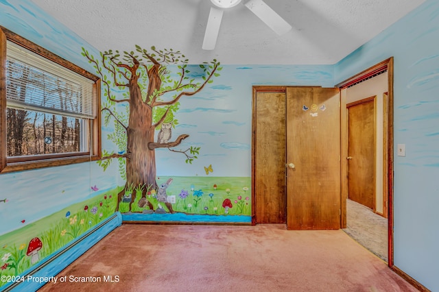 unfurnished room with a baseboard heating unit, a textured ceiling, carpet, and a ceiling fan