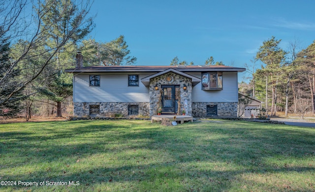 raised ranch with stone siding, a chimney, and a front yard