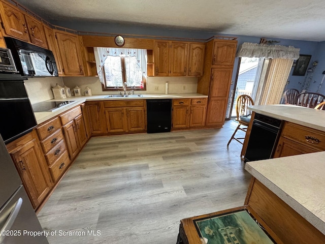 kitchen with brown cabinets, open shelves, a sink, light wood-type flooring, and black appliances