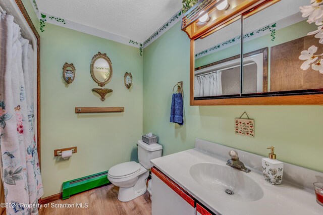 bathroom featuring toilet, a baseboard radiator, wood finished floors, a textured ceiling, and vanity