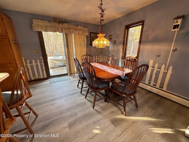 dining space with a chandelier, plenty of natural light, and wood finished floors