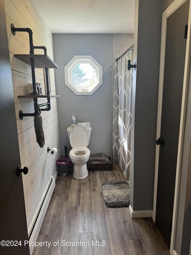 bathroom with curtained shower, toilet, wood-type flooring, and a baseboard heating unit