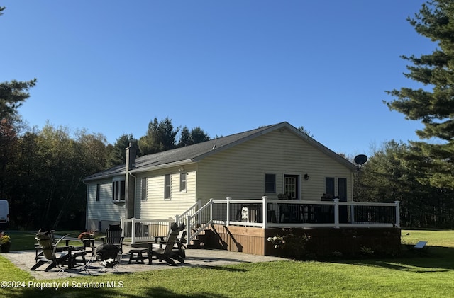 back of house featuring a fire pit, a yard, a patio, and a wooden deck