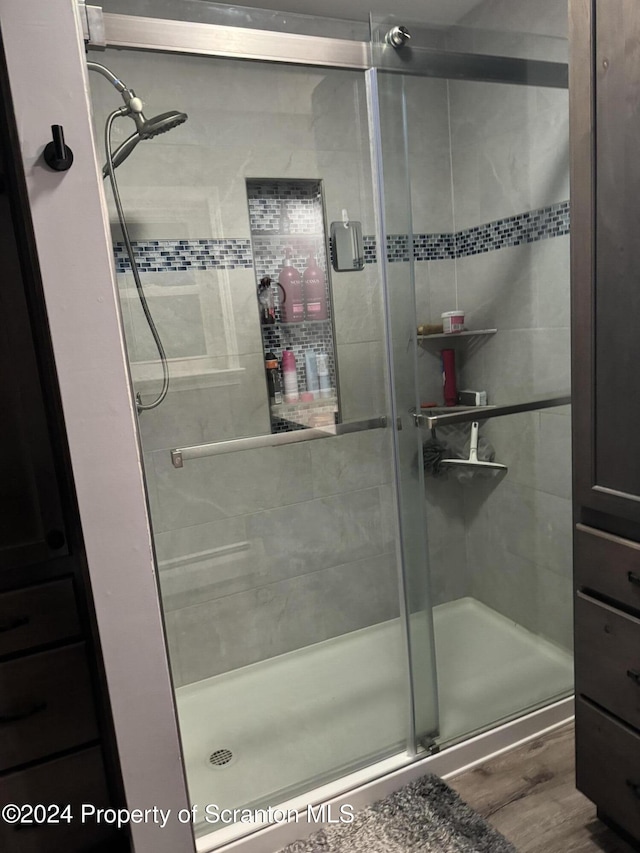 bathroom with an enclosed shower and hardwood / wood-style flooring