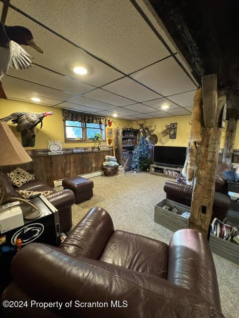 carpeted cinema room with a paneled ceiling and a baseboard heating unit