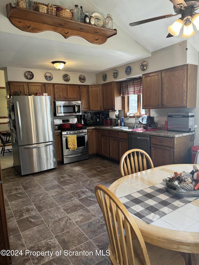 kitchen with ceiling fan, sink, stainless steel appliances, and vaulted ceiling