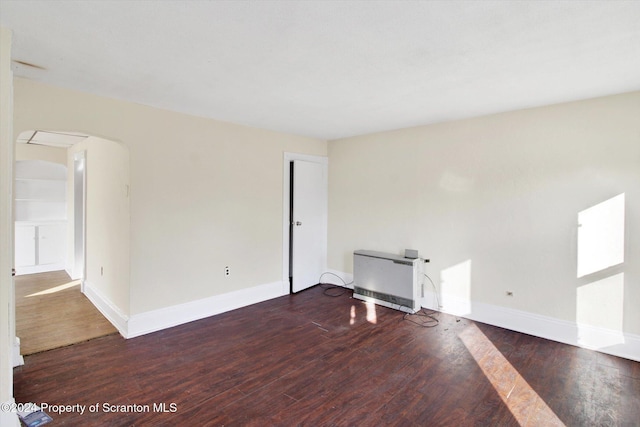 spare room with heating unit and dark hardwood / wood-style floors