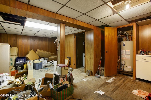 basement featuring wood walls, a paneled ceiling, and gas water heater