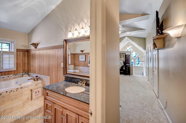 bathroom featuring tiled bath, ceiling fan, vanity, and lofted ceiling