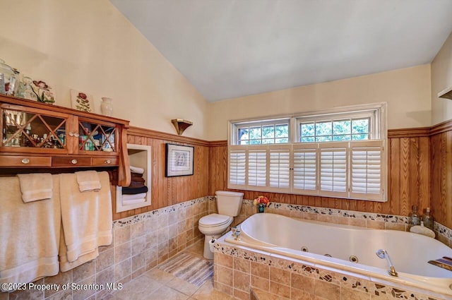 bathroom featuring tile patterned flooring, a relaxing tiled tub, vaulted ceiling, and toilet